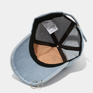 Detail of denim baseball cap interior showing 100% cotton label and metal ring