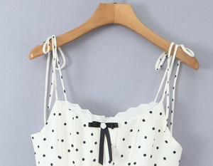 Detail of white polka dot dress with delicate lace trim and black ribbon bow