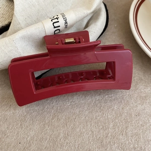 Detailed macro view of a dark red square hair claw clip with a golden metal spring
