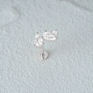 Macro detail of silver flat-back cartilage stud earring with pear and round crystals