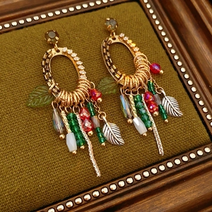 Detail of vintage bohemian tassel earrings with rhinestones and green leaf charms