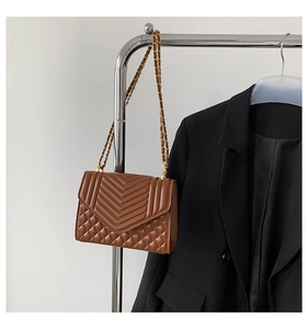 Close-up of brown quilted shoulder bag with V-shaped stitching and gold chain strap