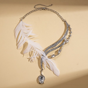 Silver feather necklace with crystals and large pear-shaped drop pendant on beige surface