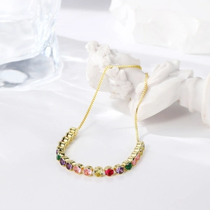 Artistic close-up of a gold adjustable bracelet with sparkling rainbow cubic zirconia stones