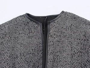 Detail of round neckline with herringbone pattern and black leather piping edges