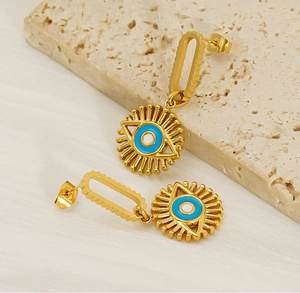 Macro di orecchini placcati in oro malocchio con smalto blu su pietra di travertino