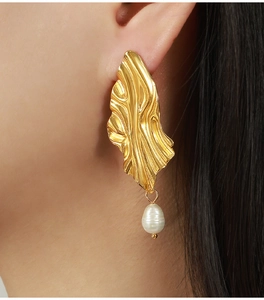 Détail de boucles d'oreilles irrégulières plaquées or avec perles baroques sur un mannequin