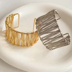 Détail de bracelets joncs en fils métalliques dorés et argentés sur plateau céramique