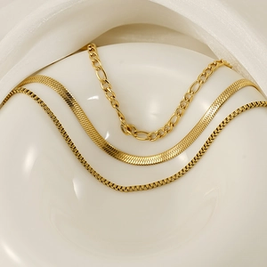 Detailed view of 18K gold plated layered chains including snake, box, and figaro styles