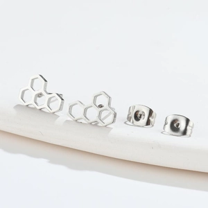 Detail of silver honeycomb stud earrings with hollow geometric hexagon design and butterfly backs