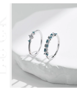 Detailed view of S925 silver rings with mint green and white stones on white stone base