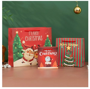 Three sizes of Christmas paper gift bags with Santa and reindeer motifs in a festive setting