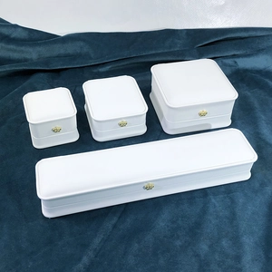 Set of four white PU leather jewelry boxes with gold crown accents on dark velvet