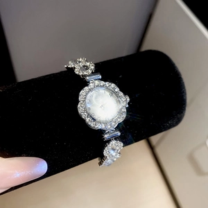 Detail of silver rhinestone floral watch on black display stand with chain bracelet
