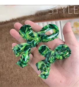 Macro detail of large and small marble texture acetate bow hair claws held in hand
