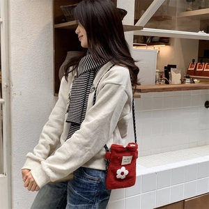Detail of red plush crossbody bag with white knit flower and sorakka beaute woven label