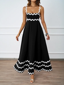 Detail of elegant black maxi dress featuring intricate white scalloped trim and flowy A-line hem