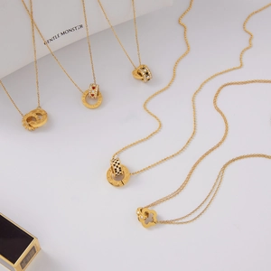 Detalle de cinco collares de acero inoxidable dorado con varios colgantes circulares en blanco