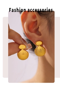 Macro view of gold-plated shell earrings showing geometric texture and stripe details