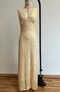 Detail of elegant yellow lace maxi dress with V-neckline and intricate white embroidery