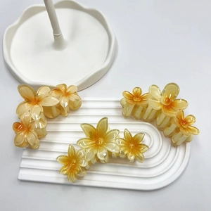 Tre fermagli per capelli a forma di fiore giallo trasparente su un vassoio bianco