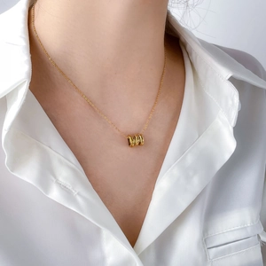 Detail of model wearing a three-ring interlocking gold pendant necklace on white satin