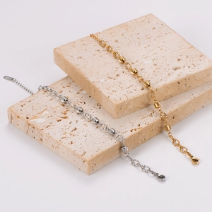 Detailed shot of gold and silver hollow cylindrical bead bracelets on textured stone