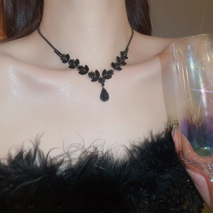 Detail of a black wheat drop pendant necklace on a model in a luxury party setting