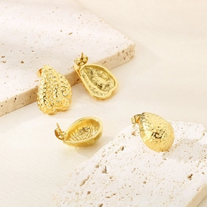 Minimalist golden teardrop earrings with hammered texture on white marble stone