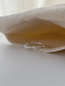Close-up of minimalist S925 sterling silver twist knot ring on a linen fabric background