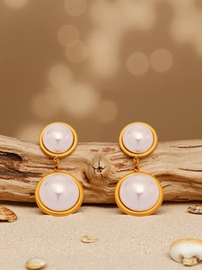 Macro detail of elegant golden double circle earrings with white pearls on a natural wood base