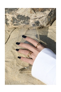 Detail of gold liquid texture S925 silver rings on hand with beach background