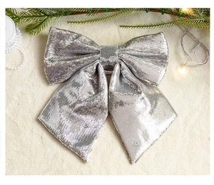 Close-up of silver sequin bow ornament with pine needles and warm fairy lights decor