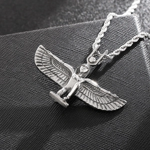Detailed close-up of silver Egyptian goddess Isis wings pendant on black textured background