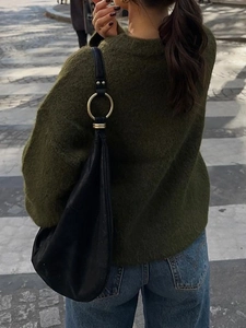 Street style view of a black leather hobo bag with a distinctive gold metal ring detail
