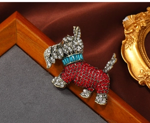 Close-up of vintage dog brooch with red enamel and white diamonds in retro gold finish