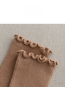 Detailed close-up of brown knit socks featuring elegant lettuce edge trim and vertical ribs