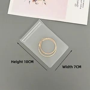 Detailed view of 7x10cm transparent EVA jewelry bag with golden twisted hoop earrings