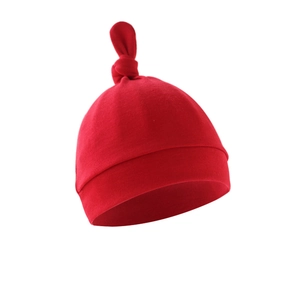 Close-up of a red knotted baby hat made from soft cotton fabric on a white background