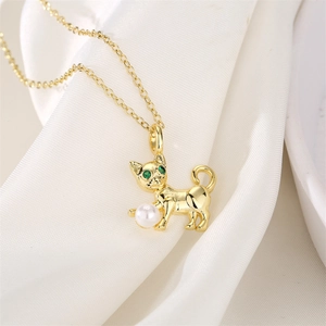 Macro detail of a golden cat pendant with green zircon eyes and a white pearl accent