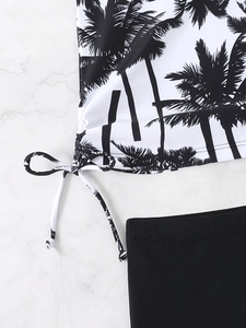 Detail of swimsuit side drawstrings and tropical palm tree print on elastic fabric
