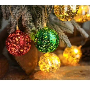 Detail of colorful vintage mercury glass ball lights hanging on a snowy Christmas tree