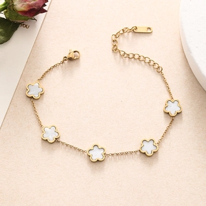 Detailed shot of gold-plated double chain bracelet with white five-petal flower charms
