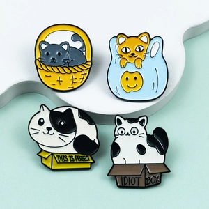 Detail of four cartoon cat enamel pins in boxes and baskets on a decorative prop