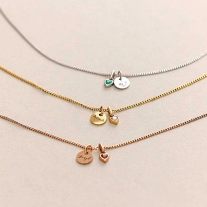 Detailed view of custom engraved pendants with colorful birthstones on thin metal chains