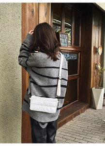 Detailed view of white quilted crossbody tote bag with wide strap on female model