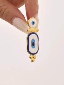 Detail of gold evil eye earrings with blue and white enamel drops held by hand
