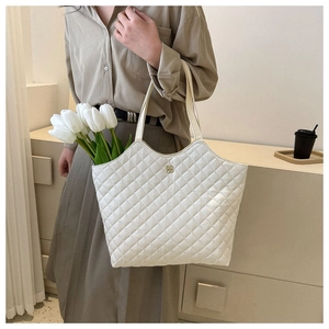 Détail du sac cabas matelassé blanc avec emblème trèfle doré et tulipes fraîches