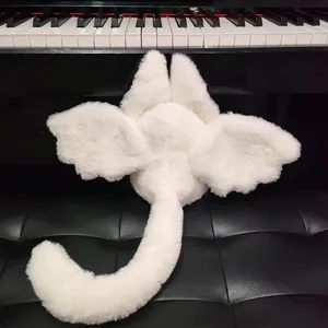 White plush bat-rabbit doll with cute wings and tail on a piano keyboard background
