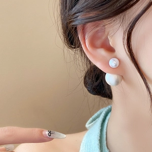 Close-up of elegant double pearl stud earrings worn by a model in a French vintage style